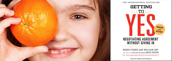 Female child holding an orange over her right eye and smiling, juxtaposed next to the cover of the book Getting To Yes