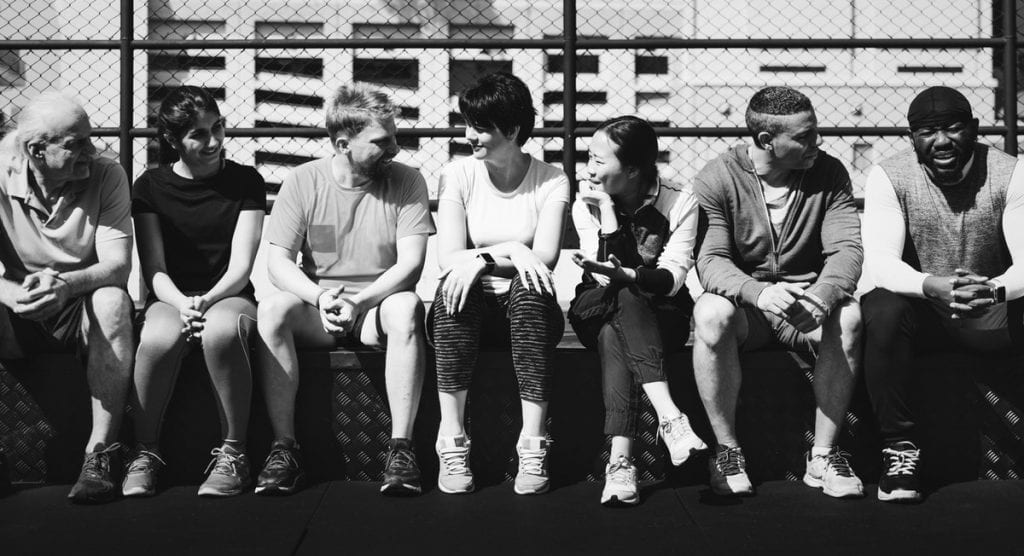 Black and white photo of seven diverse people sitting outside talking with one another