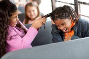 Bully on school bus pulling girl's braids