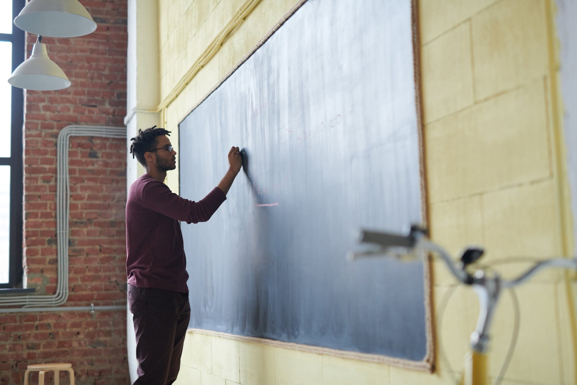 Teacher in modern style classroom writing on a chalkboard
