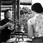 Woman watering plant and talking to other woman