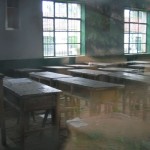 Desks in a classroom as seen through a window