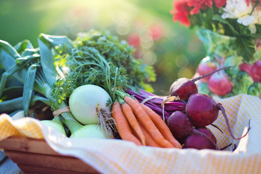 A basket of vegetables, including carrots, onions, and beets. 