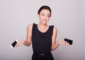 Woman holding two cellphones shrugging