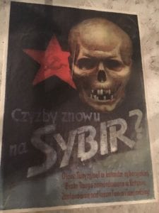 A poster with writing in Polish with a skull at the top and a red star with a hammer and sickle in it
