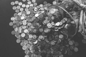a black and white photo of coins spilling out of a glass jar