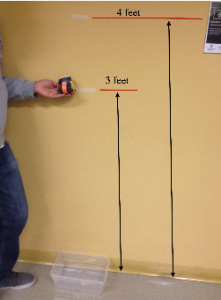 A person standing next to two vertical black lines on a wall, one 3 feet, the other higher