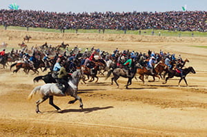 Horsemen running across a dirt field