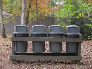 4 trash bins in wooden stand in park
